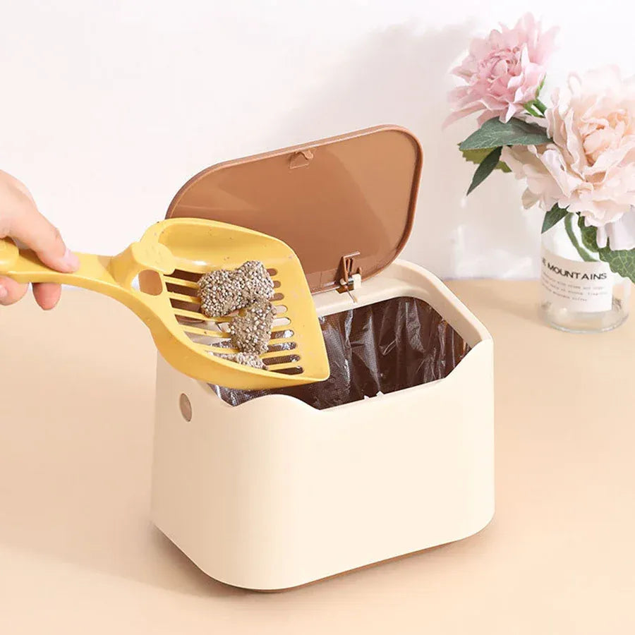 Hand scooping cat litter clumps into open beige waste bin with liner bag inside