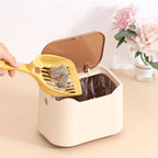 Hand scooping cat litter clumps into open beige waste bin with liner bag inside
